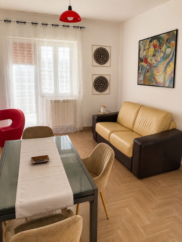 Un salon moderne avec une table à manger en verre, un canapé et deux éléments décoratifs fixés au mur.