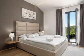 A modern bedroom with a large bed, a headboard, a bedside table with a lamp, a wall art piece, and a view through a sliding door. - Villa with pool for 6 people, children's playground, darts, table tennis table (Dračevac)