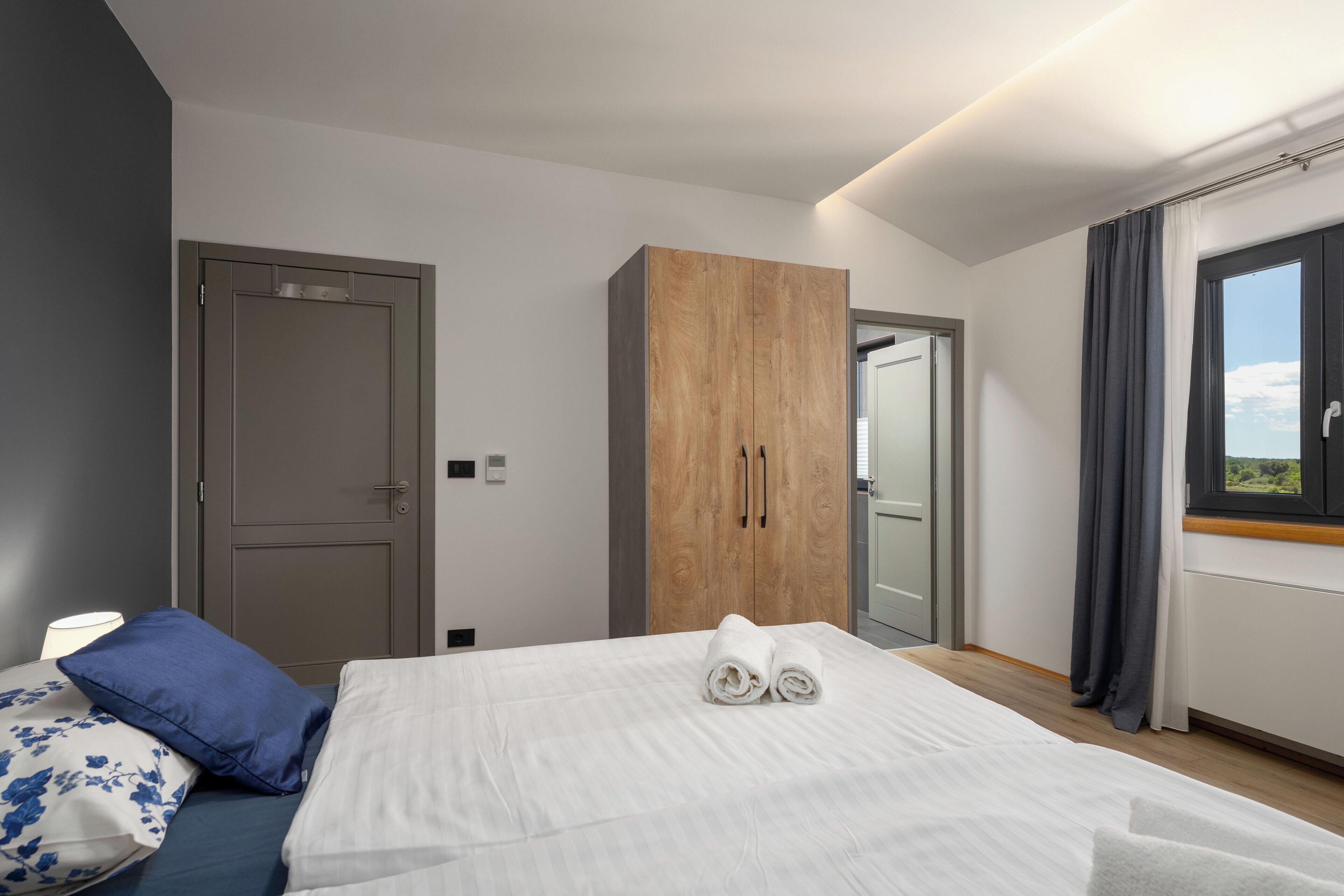 Une chambre d’hôtel avec un lit, une armoire, une porte et une fenêtre avec des rideaux.