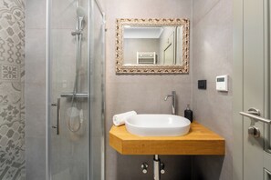 Un baño con ducha, lavamanos con espejo y toalla.