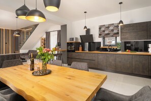 A modern kitchen with a wooden dining table, pendant lights, and a staircase leading to an upper level. - Villa with pool for 6 people, children's playground, darts, table tennis table (Dračevac)