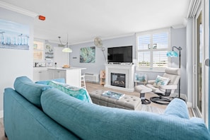 Ein Wohnzimmer mit einer Couch, einem Kamin, einem Fernseher und einem Essbereich.