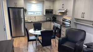 Una cocina moderna con electrodomésticos de acero inoxidable, un comedor con mesa de vidrio y una silla de cuero negro.
