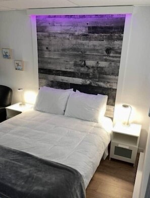 Ein Schlafzimmer mit einem Bett, zwei Nachttischen, einem Kopfteil und einer Wand mit einer strukturierten Oberfläche.
