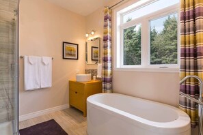 Une salle de bain avec une baignoire, un lavabo, un miroir et une fenêtre avec des rideaux.