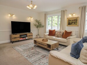 Ein Wohnzimmer mit Fernseher, Sofa, Couchtisch und einer Pflanze.