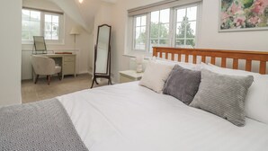 Ein Schlafzimmer mit Bett, Schreibtisch, Stuhl, Spiegel und Fenster.