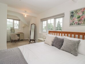 Ein Schlafzimmer mit Bett, Schreibtisch, Stuhl, Spiegel und Fenster.