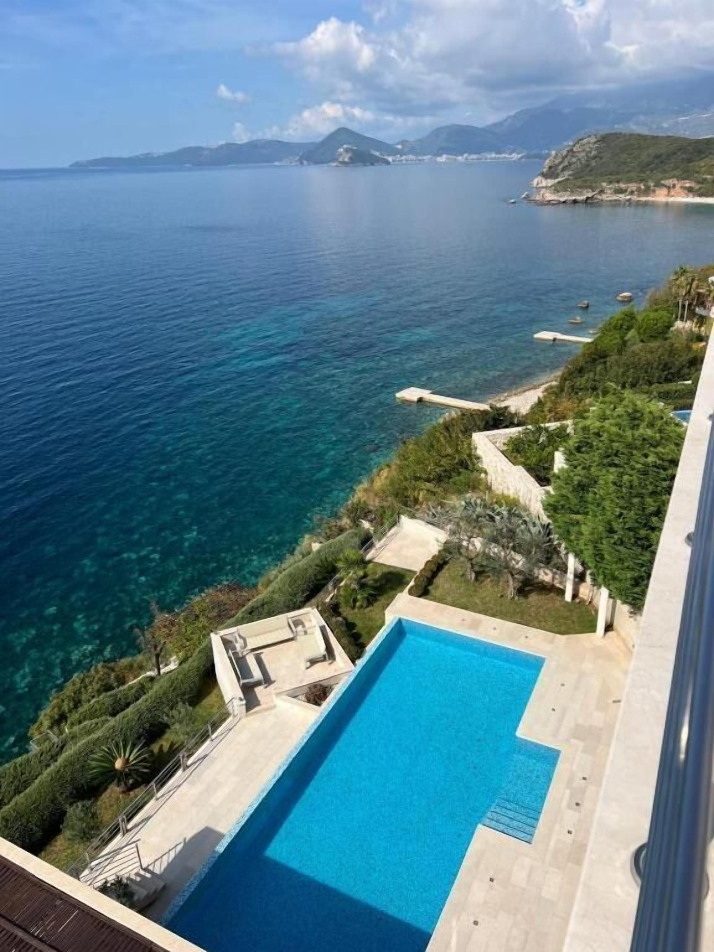 A swimming pool with a view of the sea and mountains.