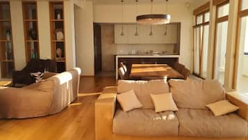 A modern living room with a sofa, a dining table, and a kitchen in the background.