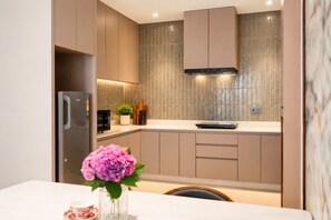 Cocina moderna con un refrigerador de acero inoxidable, un microondas y una estufa. Hay una planta en maceta sobre la encimera y un florero con flores en la mesa.