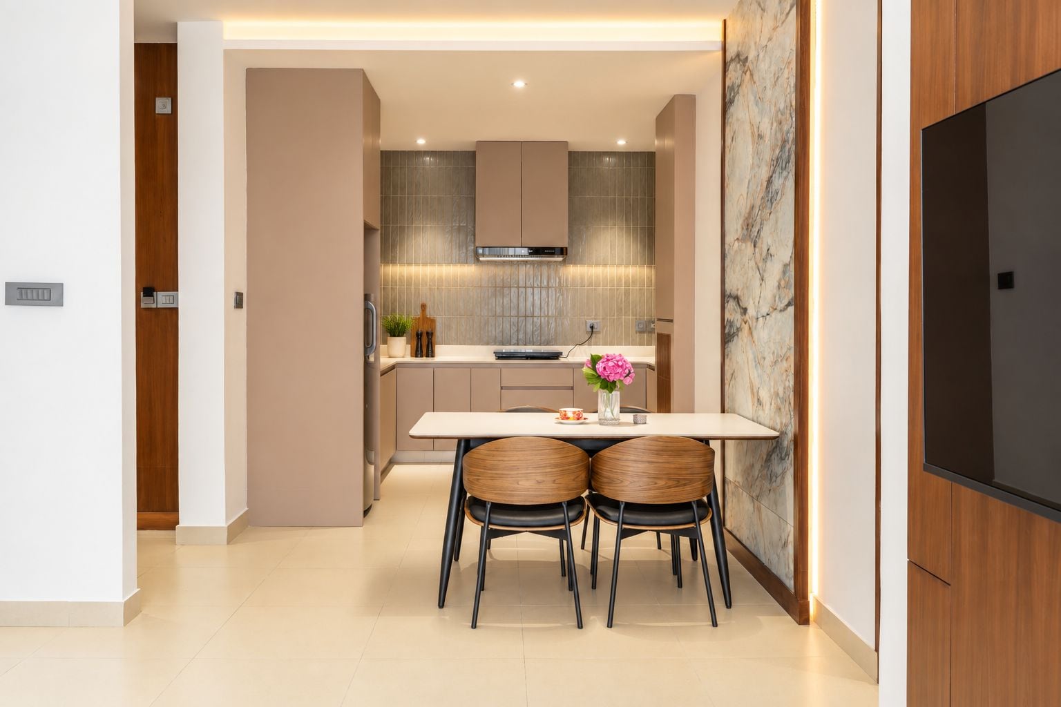 Cocina moderna con comedor, que cuenta con salpicadero de mármol, horno empotrado y televisor de pantalla plana montado en la pared.