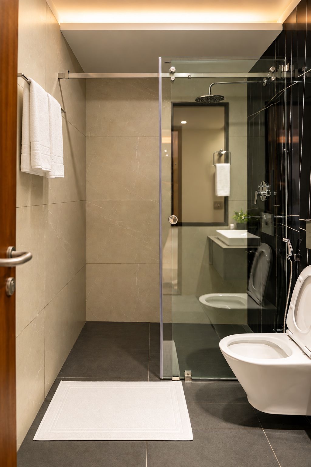 A modern bathroom with a glass-enclosed shower, a toilet, and a sink.