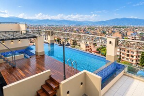 Una piscina en la azotea con vistas a un paisaje urbano y montañas.