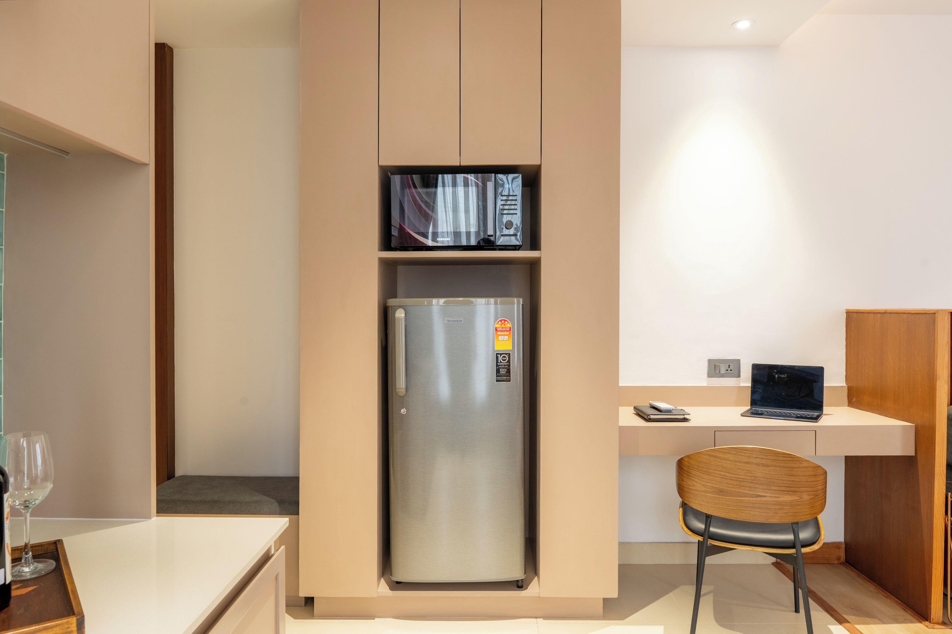 Una cocina compacta con refrigerador integrado, microondas y un pequeño comedor con una silla y mesa.