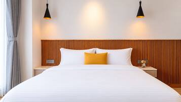 A hotel room with a large bed, two bedside tables, a wooden headboard, and two pendant lights.