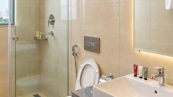 Un baño moderno con ducha envuelta en vidrio, un lavamanos grande y un espejo.