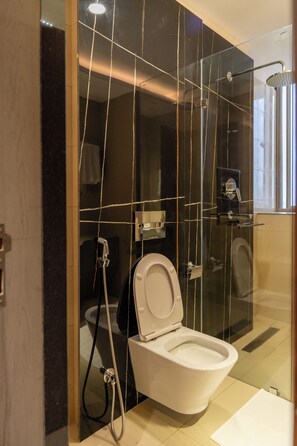 Un baño moderno con ducha envuelta en vidrio, inodoro con función bidé y un perchero visible.