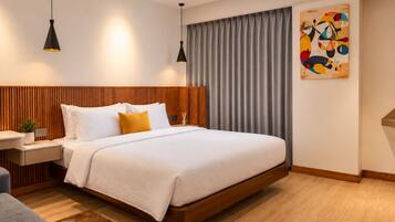 Una habitación de hotel moderna con una cama grande, cabecera de madera, mesitas de noche, un escritorio y un cuadro en la pared.