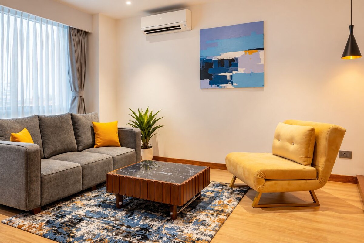 Una sala de estar moderna con un sofá gris, un sillón amarillo y una mesa de centro.