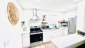 Een moderne keuken met witte kastjes, een roestvrijstalen fornuis, een magnetron en een koelkast.