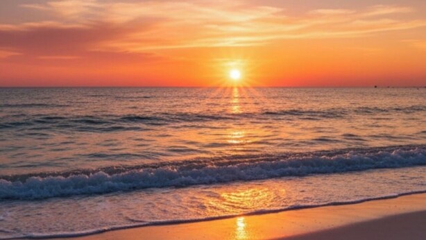 Solnedgang over havet med bølger på stranden.