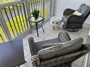 En balkon med fletningsmøbler, et lille rundt bord og en potteplante.