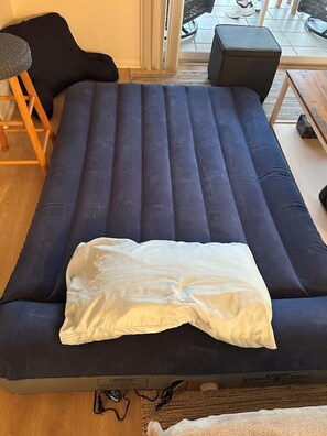 Et værelse med en mørkeblå sofa, en lille træskammel og en bænk.