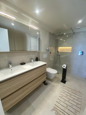 Une salle de bain moderne avec un double vasque, des toilettes, une douche et un miroir.