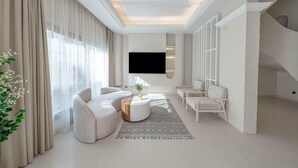 Una sala de estar moderna con un televisor de pantalla plana, un sofá, una mesa de centro y una escalera.