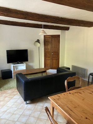 A living room with a TV, sofa, wooden table, and a cabinet. - Furnished Provencal farmhouse for 4 people in the middle of the vineyards for rent (Bollène)