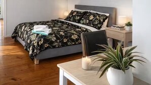 Un dormitorio moderno con cama, mesita de noche, lámpara y una planta en maceta.