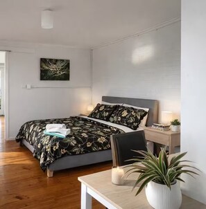 A modern bedroom with a bed, bedside table, lamp, and a potted plant. - Spacious 4-bed Retreat in Vibrant Footscray (Melbourne)