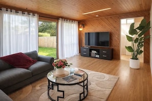 Una sala de estar moderna con un sofá, una mesa de centro de vidrio, un televisor de pantalla plana y una planta en maceta.