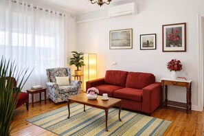 A living room with a sofa, armchair, coffee table, and a lamp. - Spacious 4-bed Retreat in Vibrant Footscray (Melbourne)