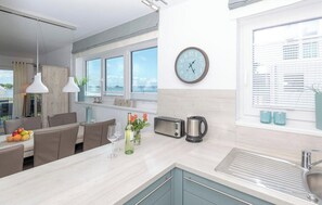 Eine moderne Küche mit einem großen Fenster, einer Uhr, einem Toaster, einem Wasserkocher und einer Spüle.