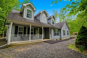 Ein zweistöckiges Haus mit Veranda, Auffahrt und gepflegtem Rasen.