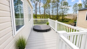 Um deck coberto com área de estar circular, corrimãos brancos e um vaso com planta.
