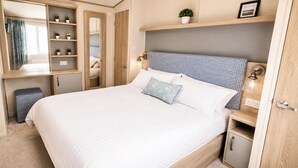 Quarto com cama, mesas de cabeceira, guarda-roupa e espelho.