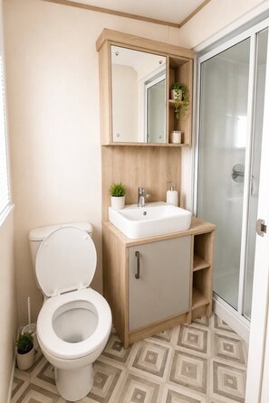 A bathroom with a toilet, sink, mirror, and shower. - Tattershall Lakes Winchester Retreat With Hot tub (Lincoln)
