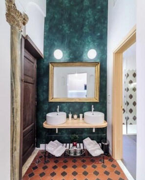 Een badkamer met twee wastafels, een spiegel en een groene wand.
