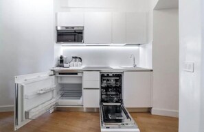 Een kleine keuken met witte kasten, een ingebouwde oven en een vaatwasser.