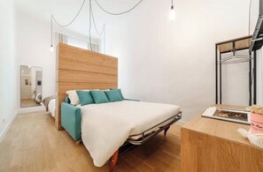 Een slaapkamer met een bed, een houten hoofdbord, een nachtkastje en een kledingkast.