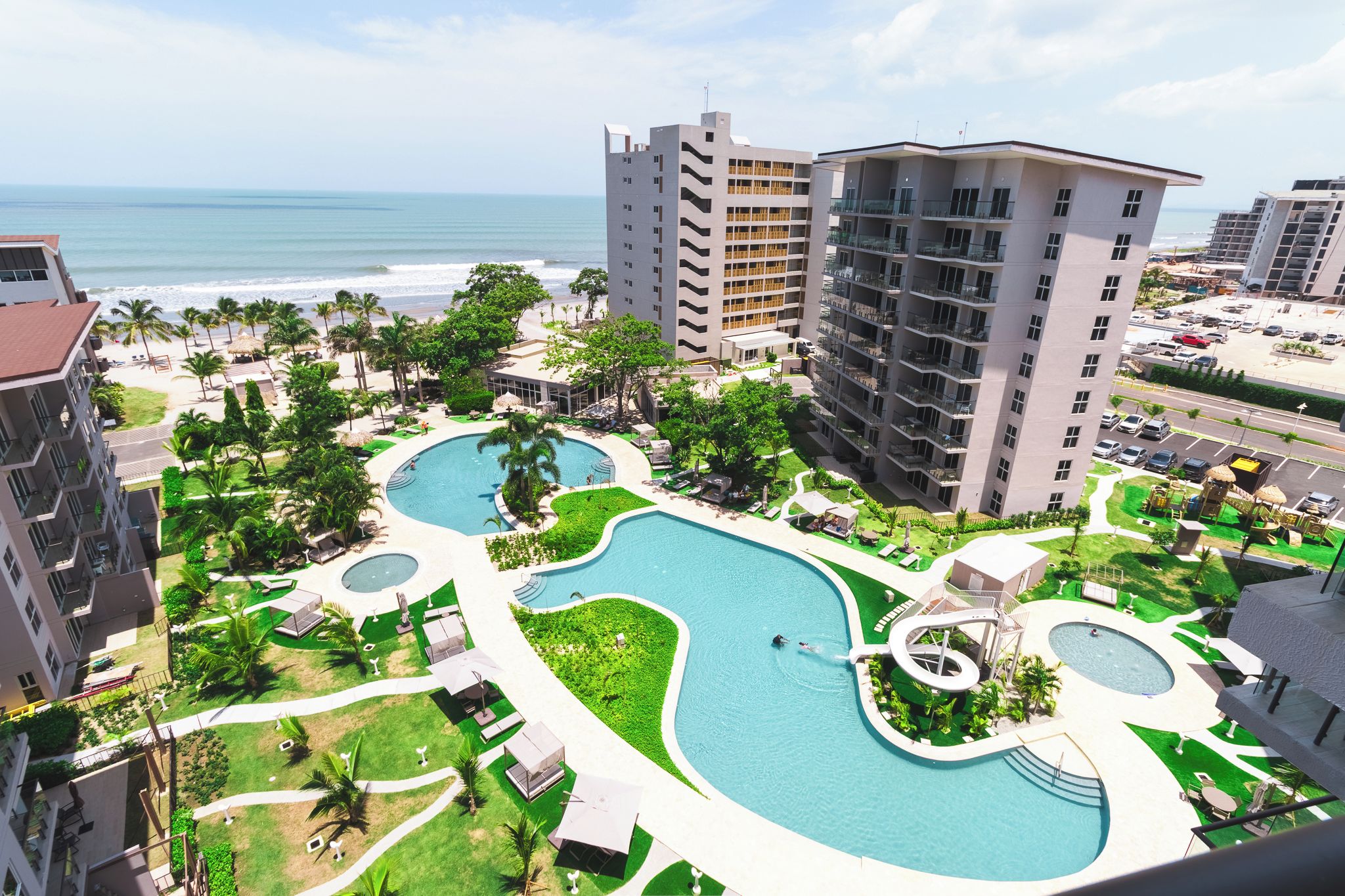 Un resort con diverse piscine, una spiaggia e alti edifici.