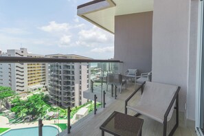 Un balcon avec une piscine, un espace salon extérieur et une vue sur le paysage urbain.