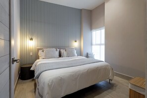 Ein modernes Schlafzimmer mit einem großen Bett, einer Wandleuchte und einem Fenster.