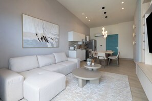 Un salon moderne comprenant un canapé d’angle, une table basse et un coin repas avec une table et des chaises.