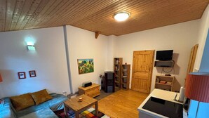 A compact living space with a sofa, a coffee table, a TV, and a kitchenette. - Hidden in the forest - cozy vacation home for quiet days in nature (Wittingen)