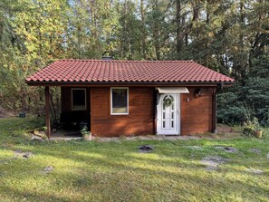 A small wooden cabin with a red-tiled roof, a white door, and a small porch. - Vrbo Property (Wittingen)