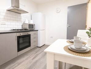 A modern kitchen with a stove, oven, microwave, and refrigerator. - The Shed - Cosy 2-Bed Flat with Free Parking - Close to City Centre (Cardiff)